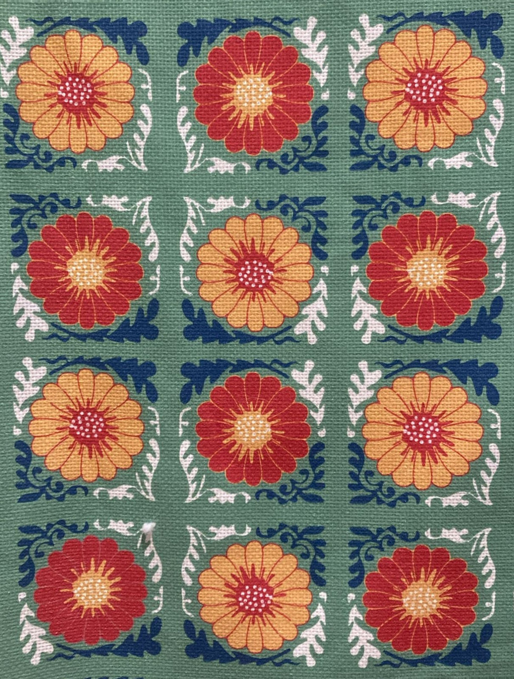 Patterned fabric with red and orange floral designs on a green background