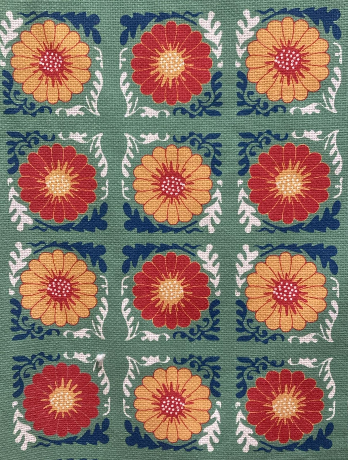 Patterned fabric with red and orange floral designs on a green background