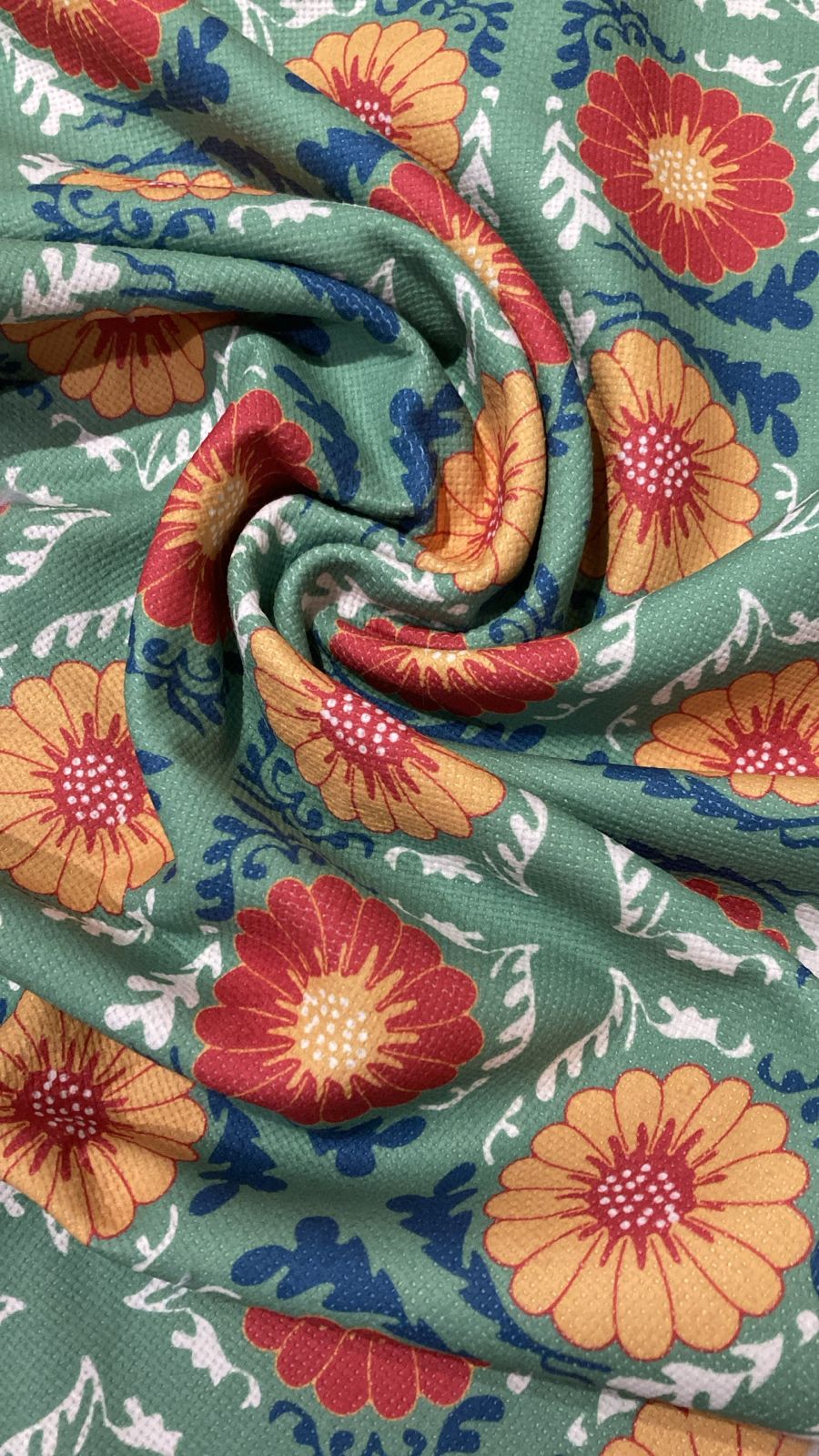 Roll of fabric with colorful floral pattern on a green background